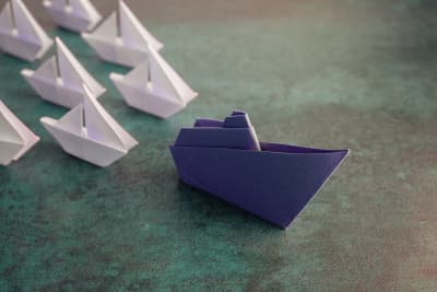 Witte papieren bootjes volgen blauwe papieren boot