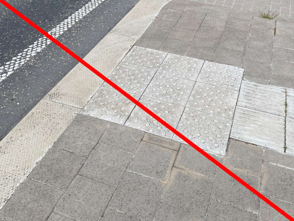 Opstapvlak uit 3 keer 3 betonnen tegels met noppen, met een rode streep over deze afbeelding.