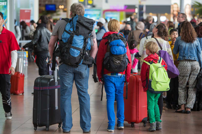 Gezin staat in luchthaven met rugzakken en reiskoffers