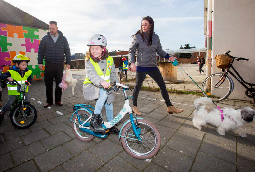 Kinderen komen met hun fiets toe op school.