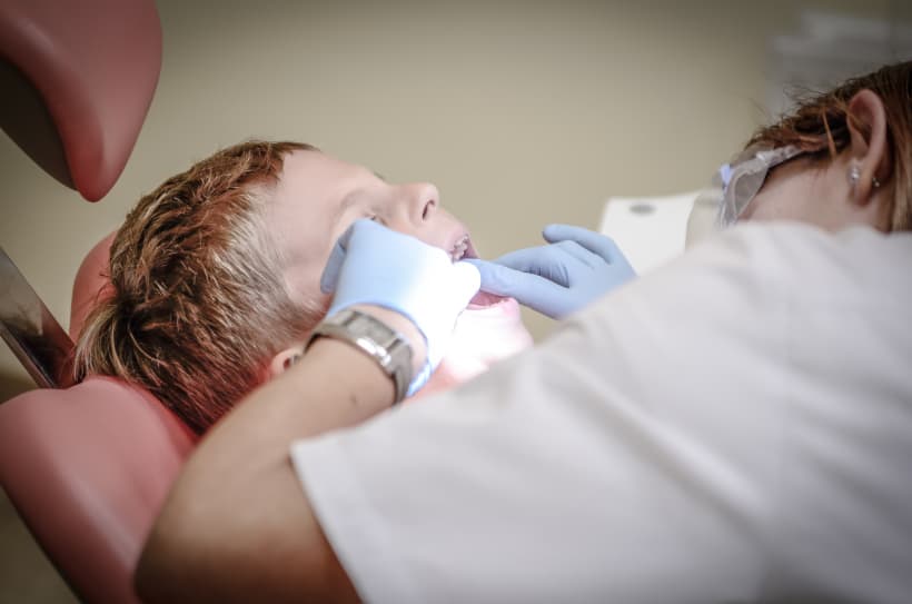 Een tandarts kijkt naar het gebit van een jongen.