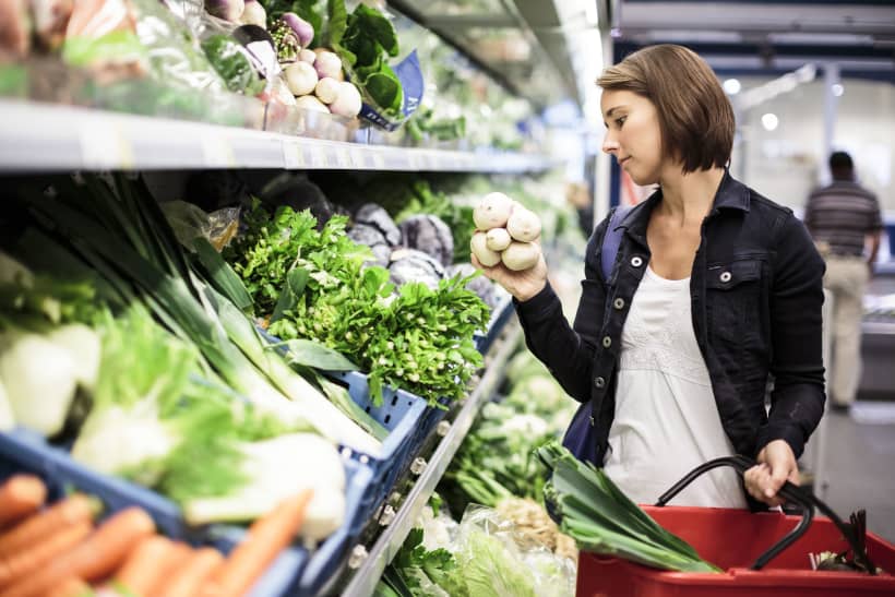Vrouw kies groenten uit in de supermarkt.