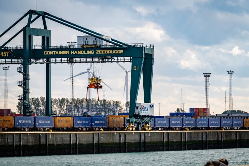 Een rij containers in de haven van Zeebrugge met een grote havenkraan