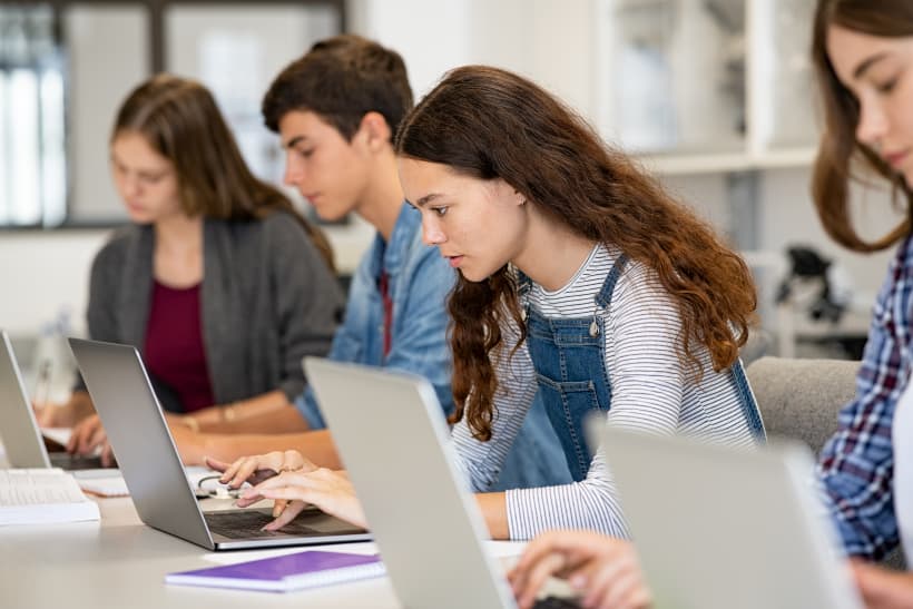 vier studenten werken individudeel en geconcentreerd naast elkaar op een laptop