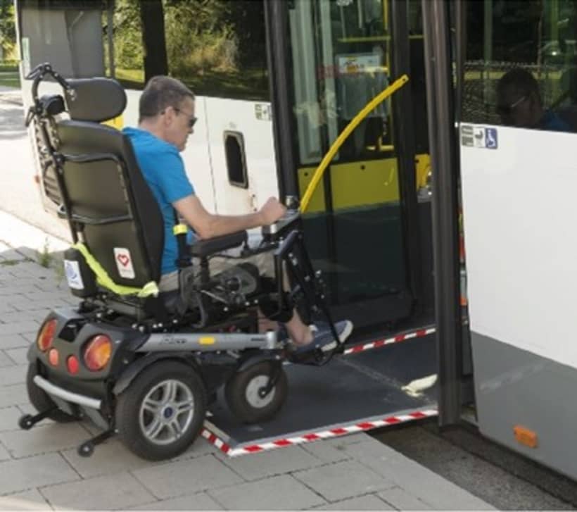 man in rolstoel neemt de bus, hij stapt op via de oprijplaat.