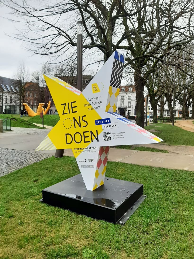 Een stervormig object staat in een park met de tekst 'Zie ons doen'