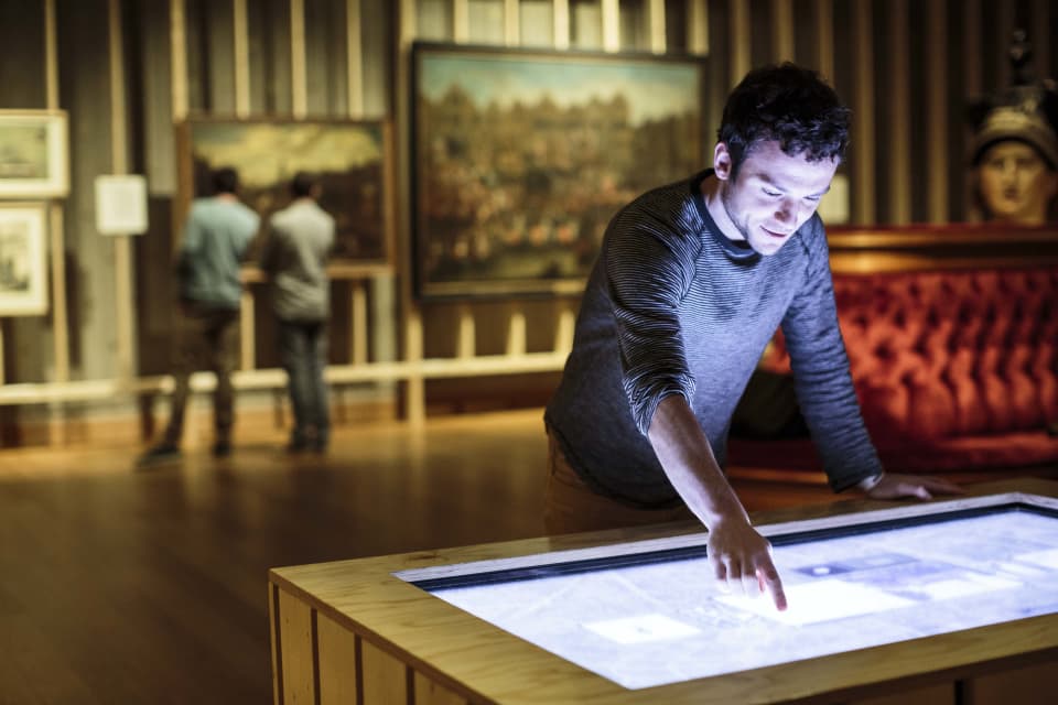 Man werkt op touchscreen in een museum.