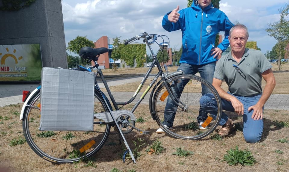 Twee personen poseren voor de fiets die één van hen gebruikt om afval te ruimen