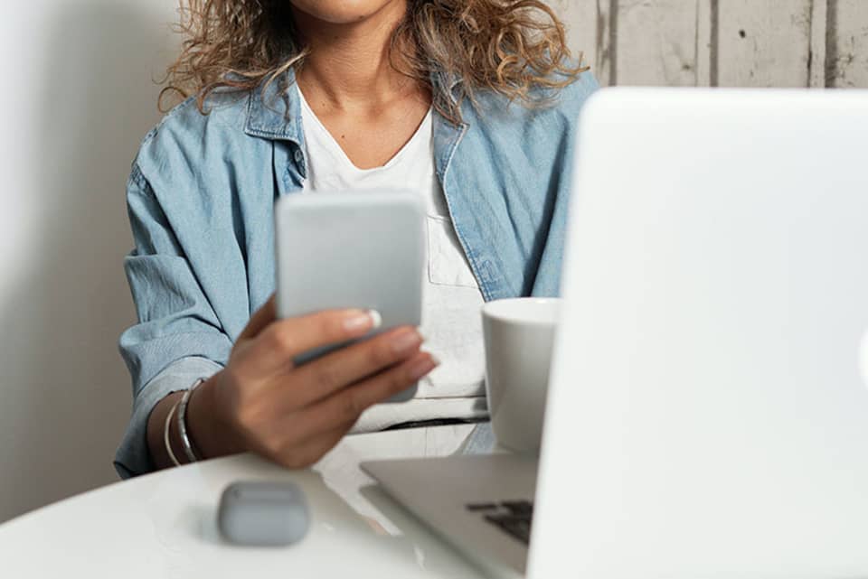 Vrouw leest nieuws op haar smartphone of laptop met een koffie